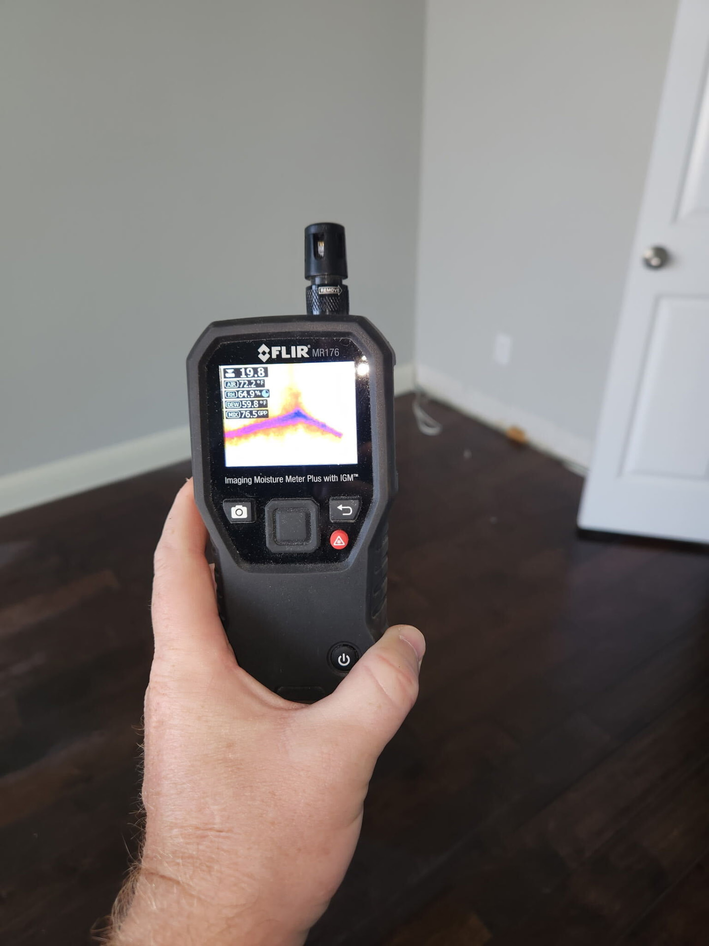 Handheld moisture meter showing a thermal view of an interior wall